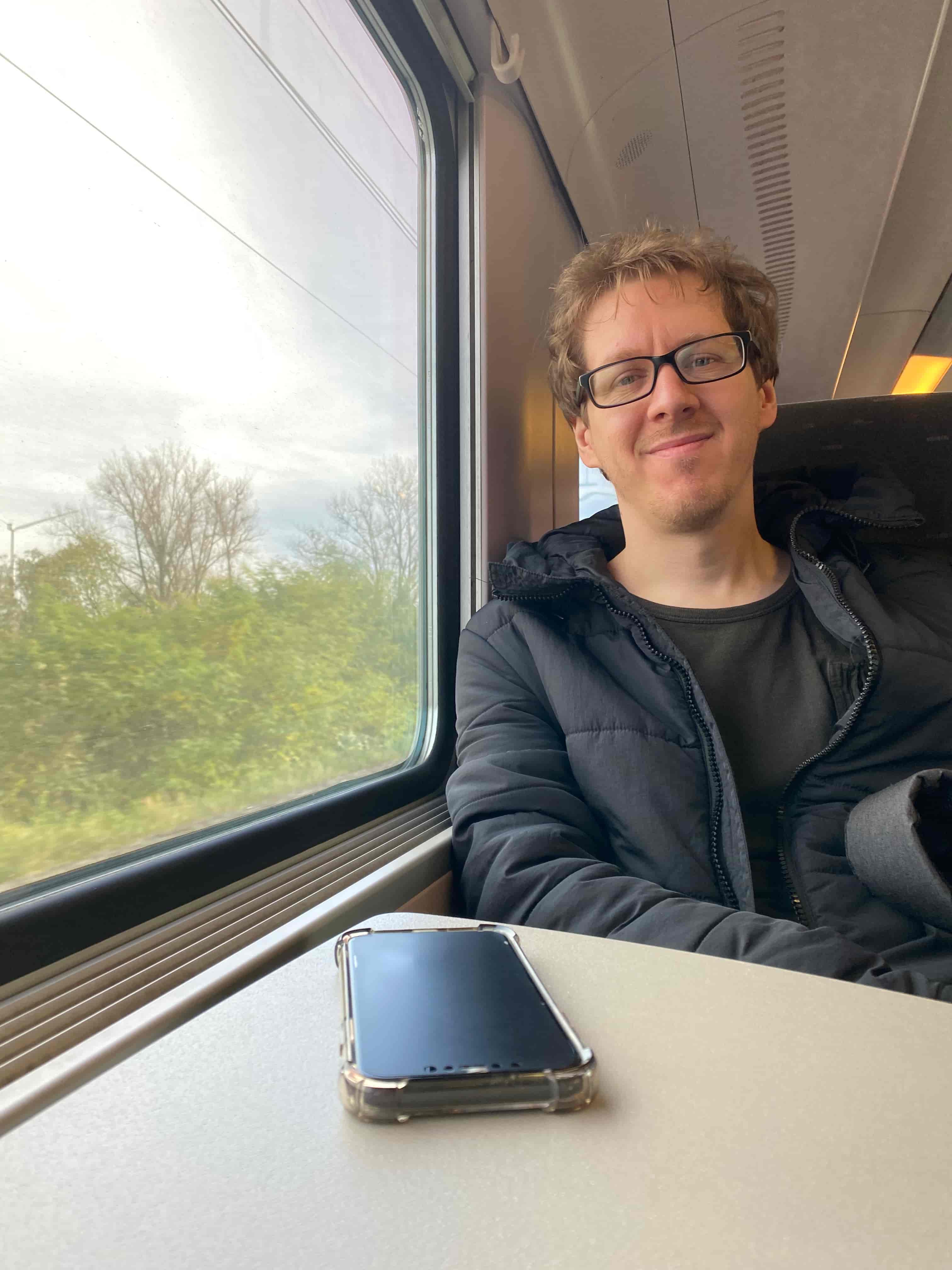 Jeanine White smiling in a red plaid shirt and tortoise shell glasses